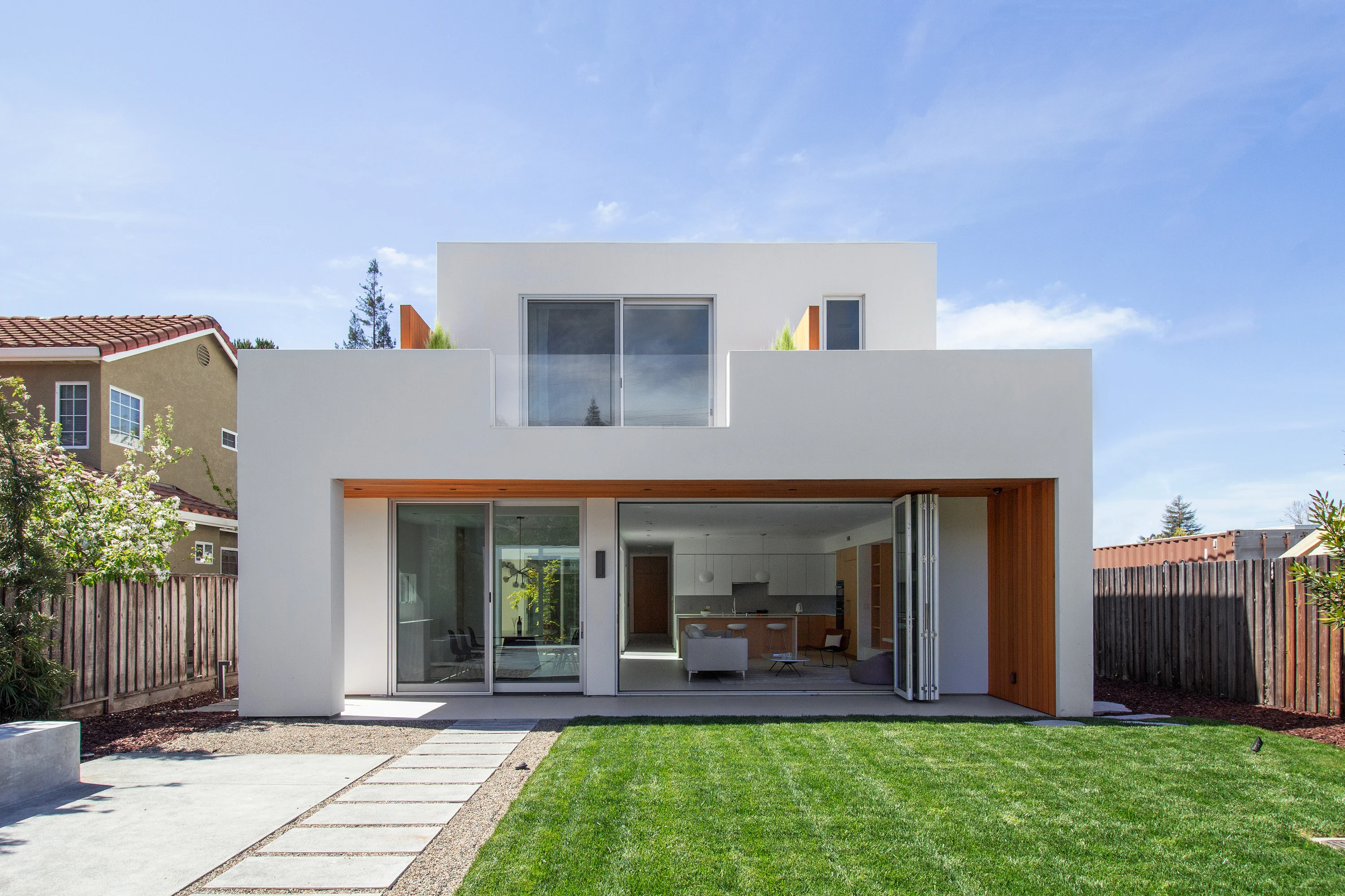 Rear elevation opening toward the lawn, with chairs and a fire pit on the concrete patio
