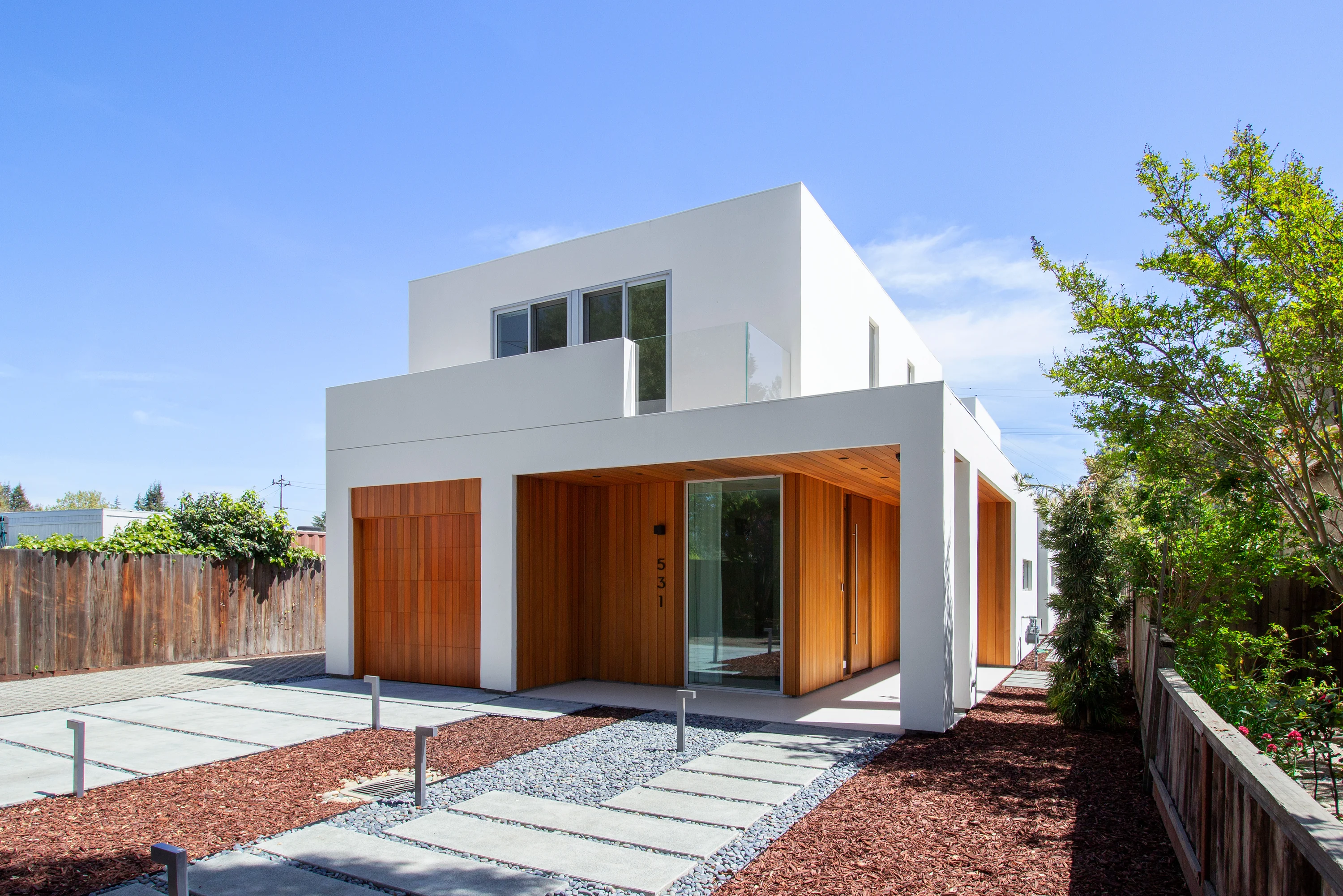 Front approach to House of Two Courtyards with white volumes and cedar-lined entry